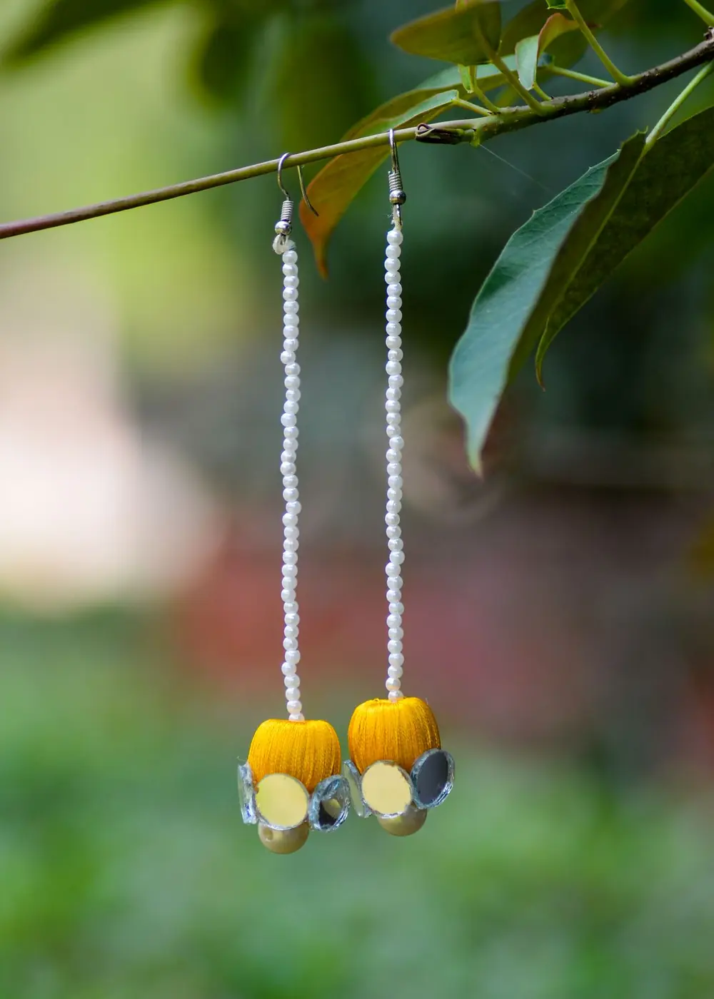 Long beaded drop earrings hanging from a branch